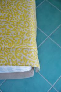 a yellow and white pillow sitting on a tile floor at Casa Adelaide in Capri