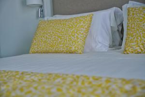 a bed with yellow and white pillows on it at Casa Adelaide in Capri