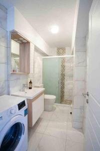 een witte badkamer met een wasmachine bij Mor Salkım Evi in Datca