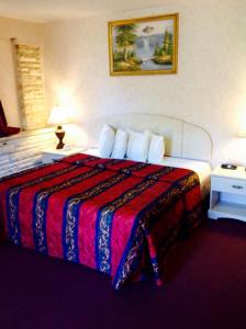 ハモントンにあるRed Carpet Inn & Suites Hammonton - Atlantic Cityのカラフルな毛布付きのベッドが備わるホテルルームです。