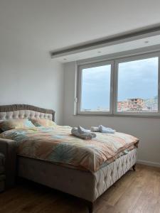 ein Bett in einem Schlafzimmer mit zwei Fenstern in der Unterkunft Apartmani IMPERIAL in Novi Pazar