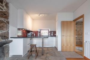 a kitchen with white cabinets and a counter with a stool at Casa da Moiroa in Sendim