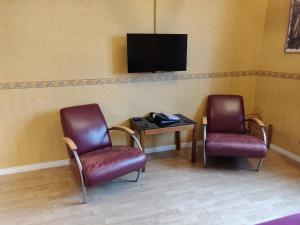 uma sala de espera com duas cadeiras e uma mesa e uma televisão em Hustugu Gård em Örsundsbro