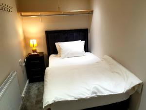 a small bedroom with a white bed and a lamp at Elegant 2 bed apartment in Manchester in Manchester