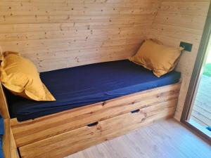 a bed in a tiny house with a wooden wall at L'arche in Muttersholtz