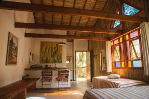 a bedroom with two beds and a kitchen with windows at Pousada Casa do Ceo in Praia do Rosa