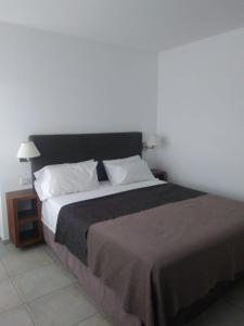 1 dormitorio con 1 cama grande con almohadas blancas en Tunkelen Carilo en Cariló