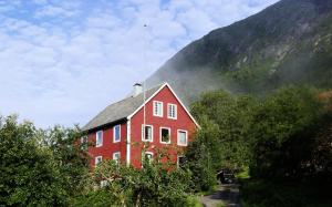 a large red house in front of a mountain at Lake View Holiday Stay in Jølster in Årdal