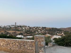 un mur en pierre avec une ville en arrière-plan dans l'établissement Sympopoula House, à Sifnos