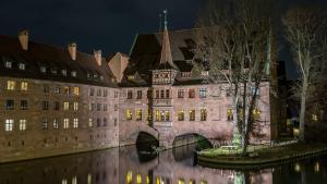 an old building with a bridge over a river at night at Convenient Appartment in Nürnberg