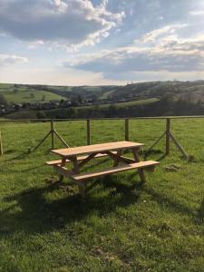 a wooden picnic table sitting in the middle of a field at Eden House 1-bedroom, horses welcome. in Whitland