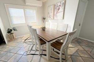 uma sala de jantar com uma mesa de madeira e cadeiras brancas em Ally’s Umina Oasis, pet-friendly spa coastal oasis em Umina