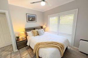 Ally’s Umina Oasis, pet-friendly spa coastal oasis في أومينا: غرفة نوم مع سرير أبيض كبير مع نافذة