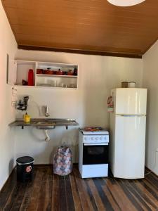a kitchen with a white refrigerator and a stove at Casa Amarela Cipó Suítes e Cipó Kombi VIP 600m centro Serra do Cipó in Santana do Riacho