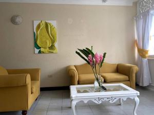 a living room with a couch and a table with flowers at Lush Tropical apartment located in a 4-star resort in Runaway Bay