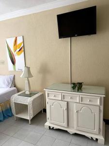 1 dormitorio con 1 cama y TV en la pared en Lush Tropical apartment located in a 4-star resort, en Runaway Bay