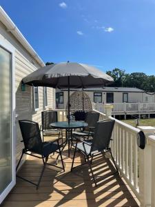 a table and chairs on a deck with an umbrella at Hoburne Beach Escape near Christchurch in Mudeford