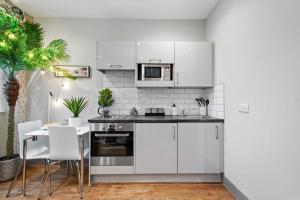 a kitchen with white cabinets and a table with chairs at Boho Jungle - Luxury 1bed Apt- Long stay Discounts in Kent