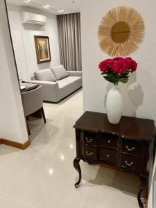 una sala de estar con un jarrón de flores sobre una mesa en Apto tipo Flat Midas Riocentro - Barra da Tijuca- Barra olímpica, en Río de Janeiro