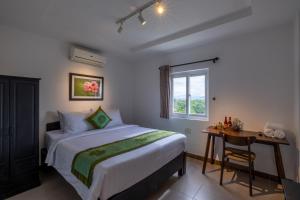 a bedroom with a bed and a desk and a window at Purple Hue - Charming Riverside in Hue