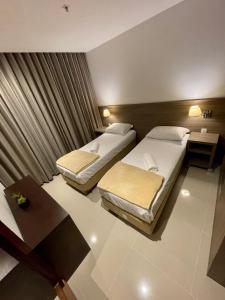 a hotel room with two beds and a table at Apto tipo Flat Midas Riocentro - Barra da Tijuca- Barra olímpica in Rio de Janeiro