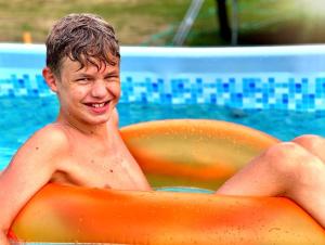 un jeune homme assis dans un radeau orange dans une piscine dans l'établissement Agroturystyka "Zielone Zacisze", à Łagów