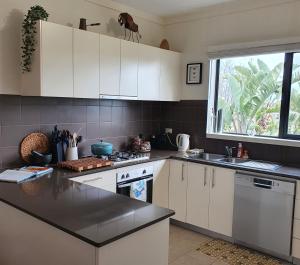 a kitchen with white cabinets and a large window at Maggie's Place in Cowes in Cowes