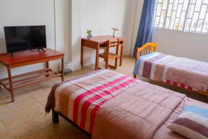 Habitación con 2 camas, escritorio y TV. en Casa Pirhua, en Piura