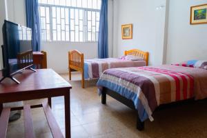 1 dormitorio con 2 camas, mesa y TV en Casa Pirhua, en Piura