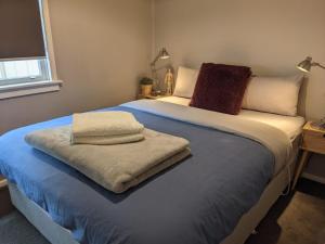 a bedroom with a large bed with towels on it at Kenna Cottage in Orange