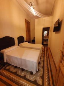 una camera d'albergo con due letti e uno specchio di Hostal Lausanne a Barcellona