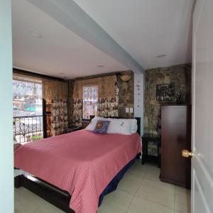 1 dormitorio con 1 cama con manta rosa en Los Andes Hostal, en Filandia