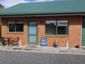 a brick house with a table and chairs in front of it at Cosy Nights - modern, self-contained with parking in Kerikeri
