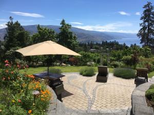 a patio with a table and an umbrella and chairs at Lakeview Gardens B&B in Peachland
