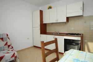 a kitchen with white cabinets and a table and a chair at Apartment Zubovici 9363a in Zubovići