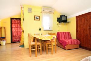 ein Esszimmer mit einem Tisch und Stühlen sowie einem TV in der Unterkunft Apartments and rooms with a swimming pool Novalja, Pag - 9334 in Novalja