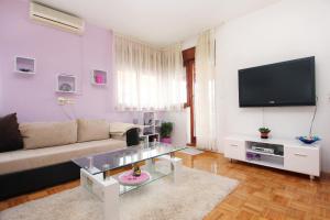 Apartments by the sea Mastrinka, Ciovo - 9447 في تروغير: غرفة معيشة مع أريكة وتلفزيون