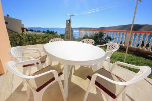 - une table et des chaises blanches sur un balcon donnant sur l'océan dans l'établissement Apartments by the sea Vlasici, Pag - 9324, à Vlašići