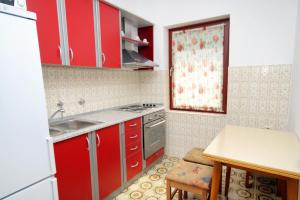 uma cozinha com armários vermelhos, um lavatório e uma mesa em Apartments with a parking space Bosana, Pag - 9374 em Pag
