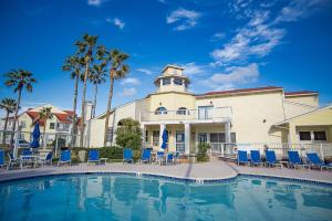 a swimming pool in front of a building with blue chairs at Oceanside Retreat in Corpus Christi