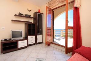 uma sala de estar com uma televisão e uma porta de vidro deslizante em Apartments by the sea Karbuni, Korcula - 9308 em Prizba