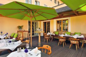 a restaurant with tables and chairs and a green umbrella at Hotel zur Post in Aschheim