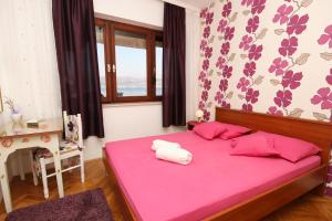 een slaapkamer met een roze bed en een raam bij Apartments by the sea Slatine, Ciovo - 9454 in Slatine
