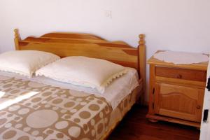 a bedroom with a wooden bed and a night stand at Secluded fisherman's cottage Cove Vela Proversa, Kornati - 9471 in Vala