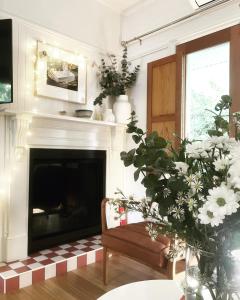 a living room with a fireplace and a chair and flowers at La Perouse Lorne in Lorne