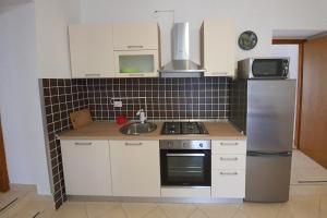 kuchnia z białymi szafkami, zlewem i lodówką w obiekcie Apartment Zubovici 9365d w mieście Zubovići