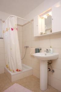 łazienka z umywalką i zasłoną prysznicową w obiekcie Apartments with a swimming pool Zubovici, Pag - 9365 w mieście Zubovići