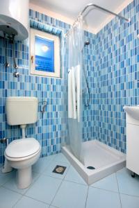 a blue tiled bathroom with a toilet and a shower at Apartments by the sea Stara Novalja, Pag - 9368 in Novalja