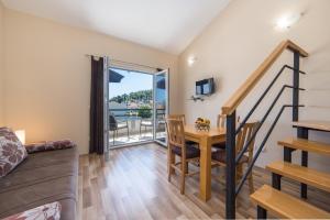 a living room with a dining room table and a balcony at Apartments by the sea Drvenik Donja vala, Makarska - 9654 in Drvenik