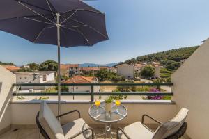 a balcony with a table and chairs and an umbrella at Apartments by the sea Drvenik Donja vala, Makarska - 9654 in Drvenik